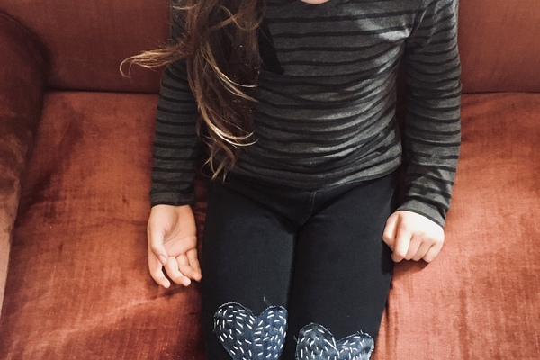 child shows off  hand sewn heart patches.