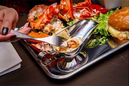 Platter of food featuring lobster, burger, salad, french fries